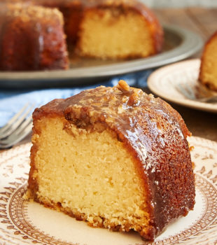 slice of Pecan Pie Bundt Cake on a brown floral plate with the remaining cake in the background