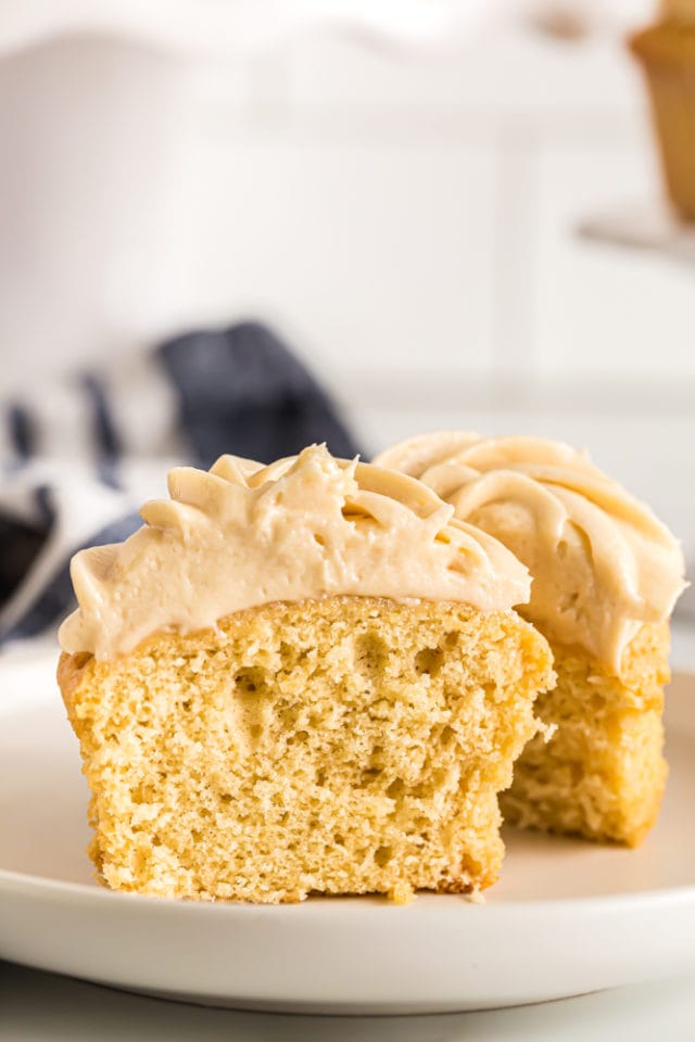 two halves of a frosted Brown Sugar Pound Cake on a white plate