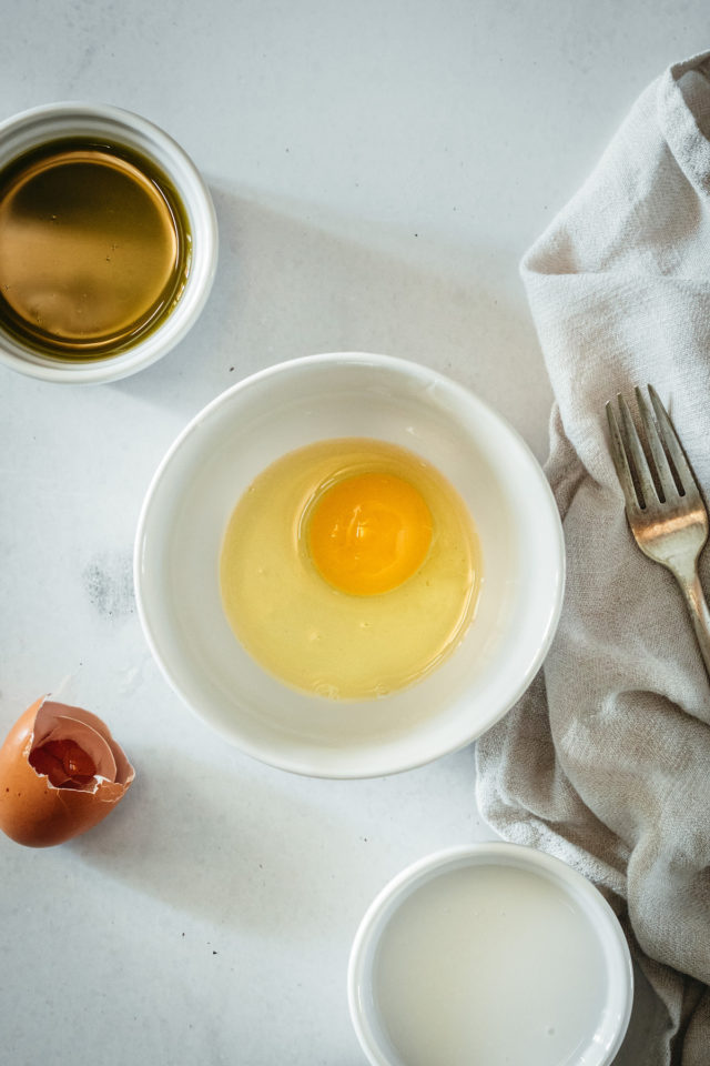 Overhead view of cracked egg in small bowl