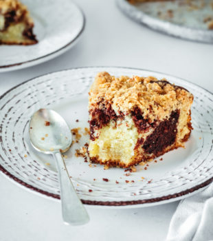 Half-eaten slice of chocolate swirl coffee cake on plate with spoon
