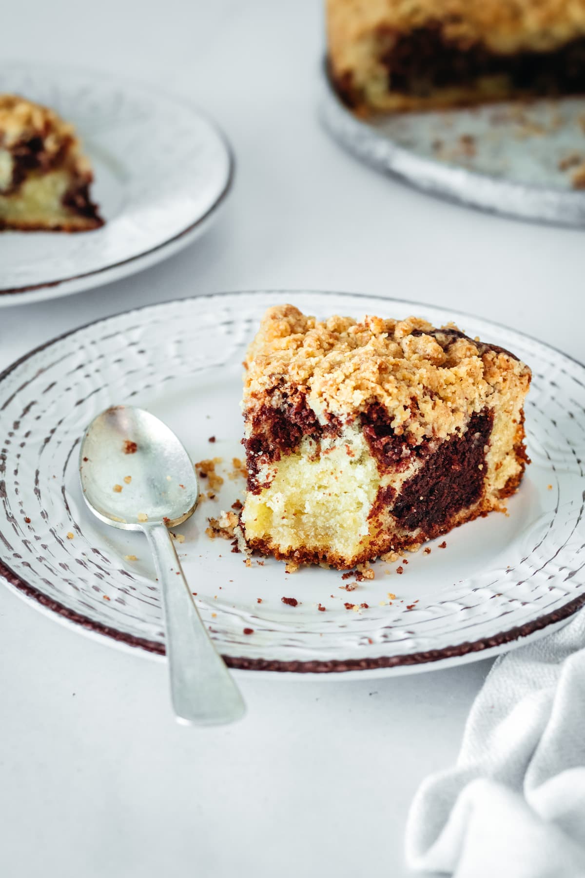 Half-eaten slice of chocolate swirl coffee cake on plate with spoon