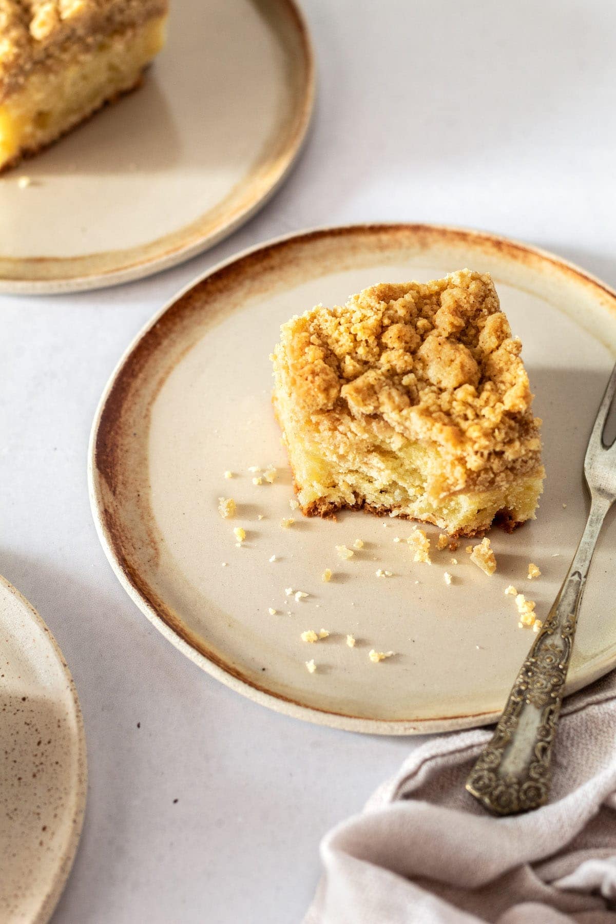 Square of crumb cake on small plate with fork