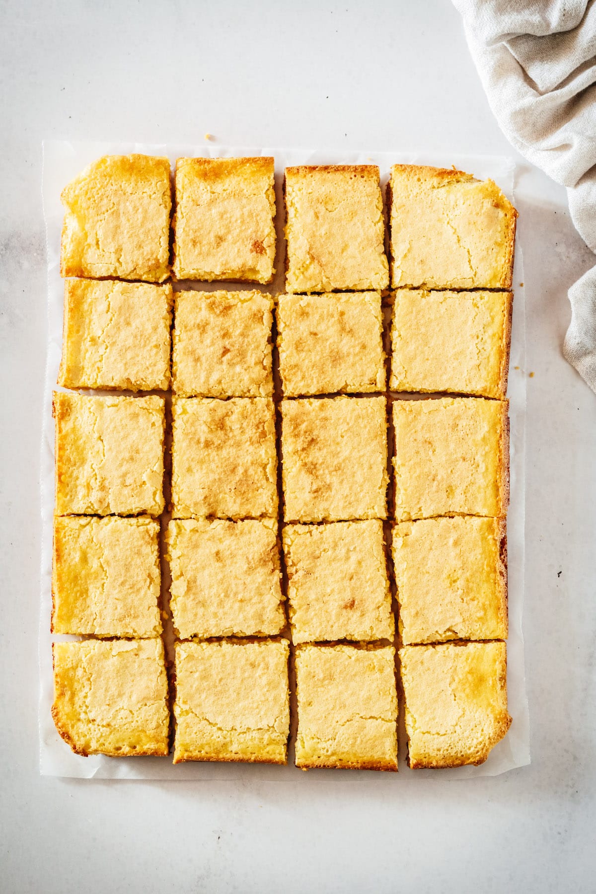 Overhead view of cut lemon bars on parchment before adding powdered sugar