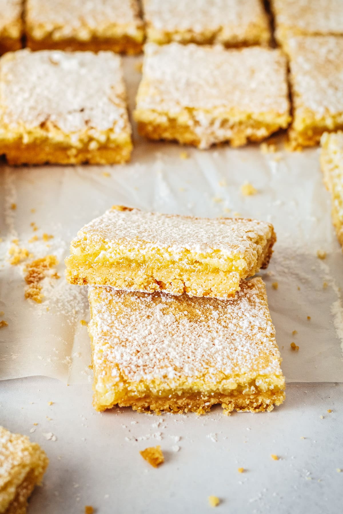 One lemon bar square stacked onto another with others in background