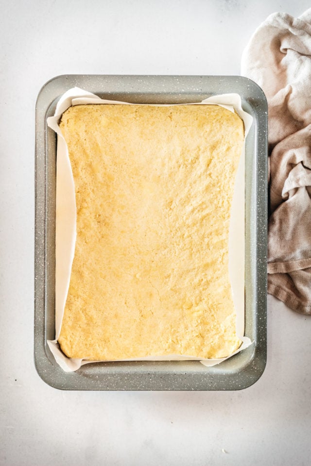 Overhead view of lemon bar crust in parchment-lined pan