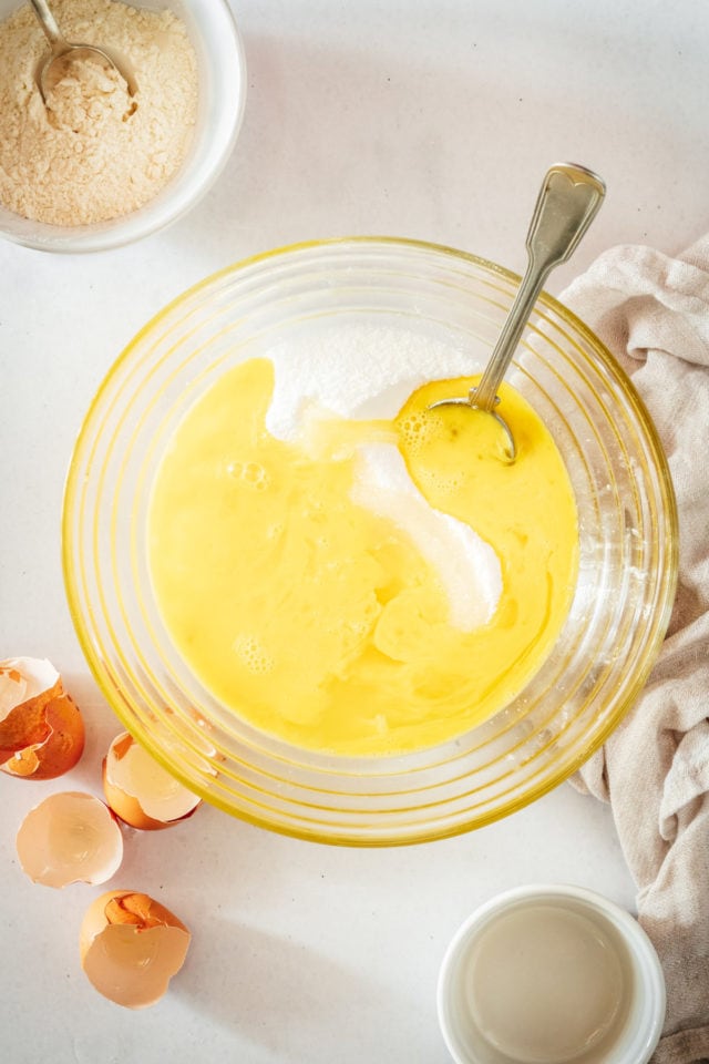 Overhead view of sugar being stirred into lemon filling in glass bowl