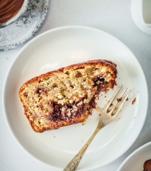 Overhead view of Nutella Banana Bread slice on plate with fork, with corner eaten