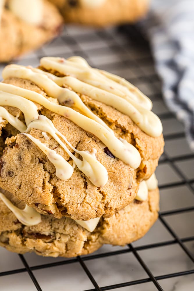 Close up of two oatmeal cranberry cookies stacked on a wire rack.