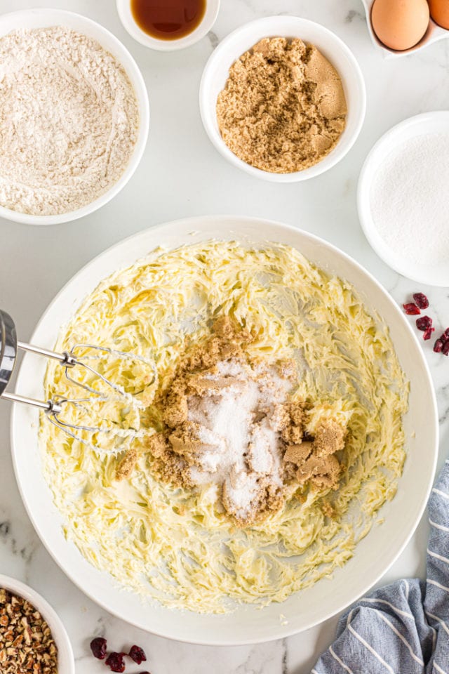 overhead view of sugars added to creamed butter in a white mixing bowl