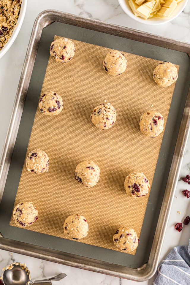 overhead view of portioned Oatmeal Cranberry Cookies dough on a silicone-lined baking pan