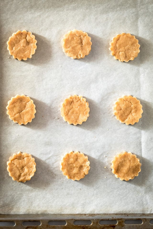 Overhead view of peanut butter cutout cookies on parchment lined baking sheet