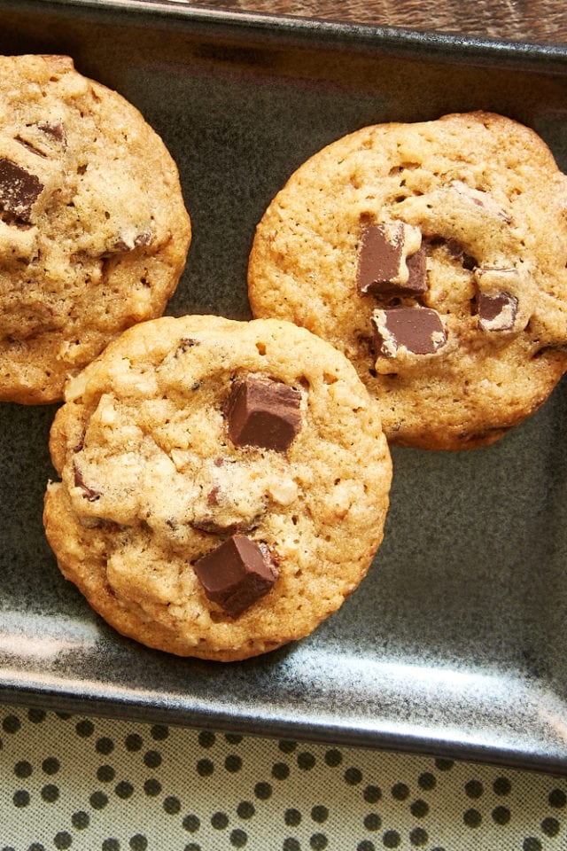 overhead view of three Bourbon Pecan Chocolate Chip Cookies on a dark gray tray