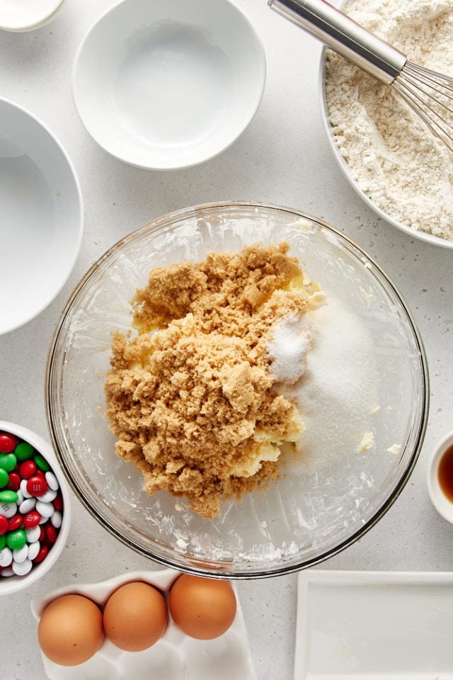 overhead view of brown sugar and sugar added to creamed butter in a glass mixing bowl