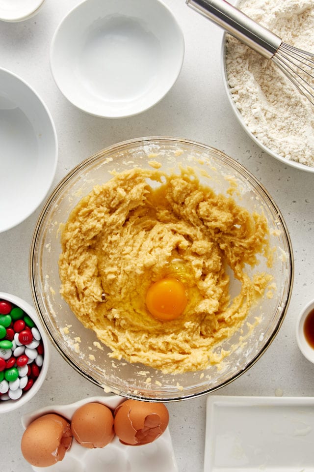 overhead view of egg added to cookie dough in a glass mixing bowl