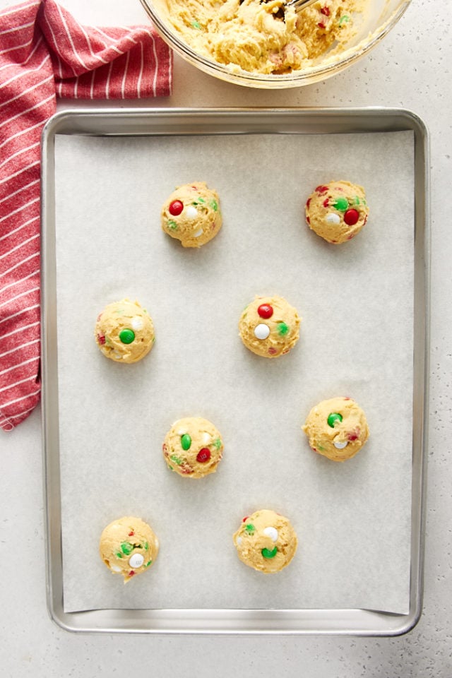overhead view of Christmas M&M Cookies dough portioned and placed on a parchment-lined baking sheet