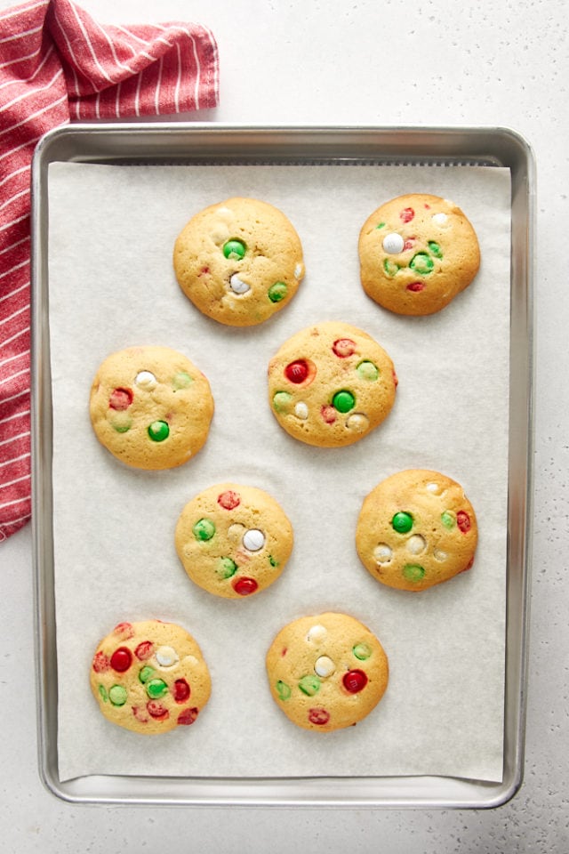 overhead view of freshly baked Christmas M&M Cookies on a parchment-lined baking sheet
