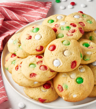 Christmas M&M Cookies piled on a white plate with M&Ms scattered around the plate