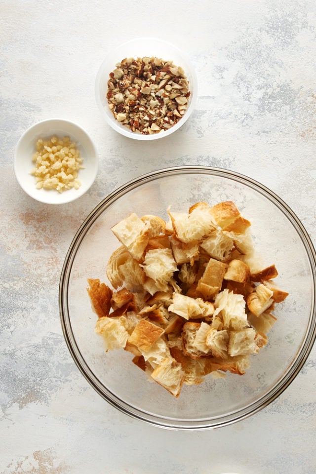 overhead view of cubed croissants, almond paste, and almonds in bowls