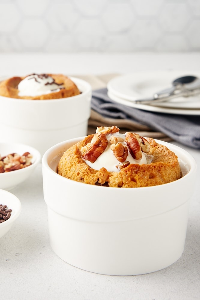 a Deep Dish Chocolate Chip Cookie topped with ice cream and nuts with another cookie in the background