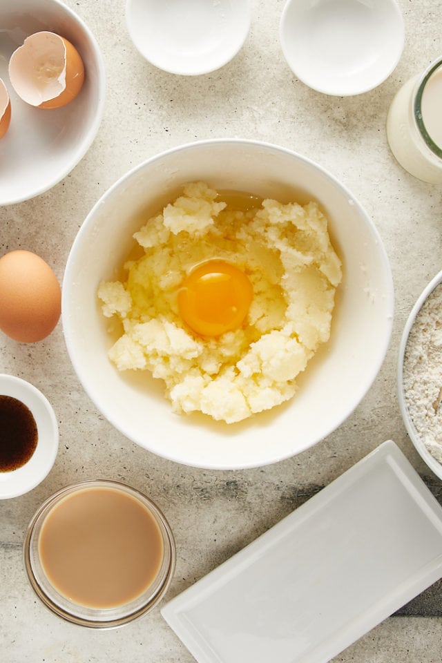 overhead view of egg added to other wet ingredients in a white mixing bowl