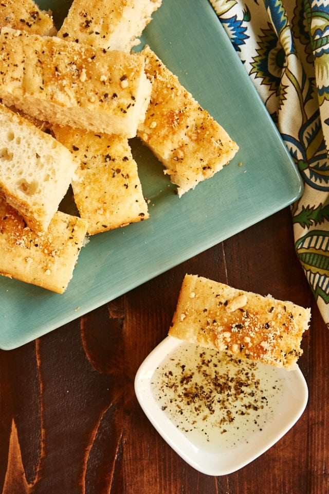 overhead view of No-Knead Focaccia served on a green plate and with a bowl of olive oil for dipping