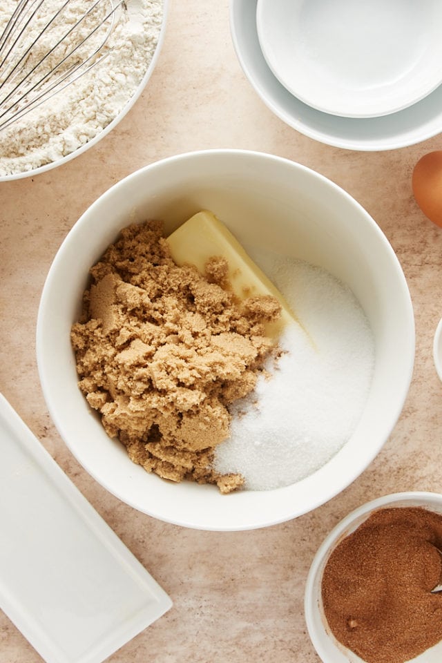 overhead view of butter, brown sugar, and granulated sugar in a white mixing bowl