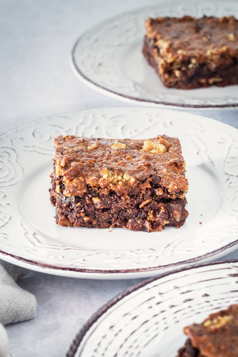 Caramel coconut pecan brownies on white plates.