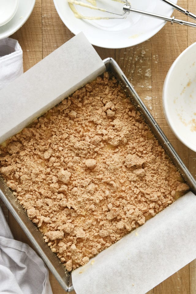 overhead view of crumb topping added to Almond Crumb Cake batter in a square baking pan