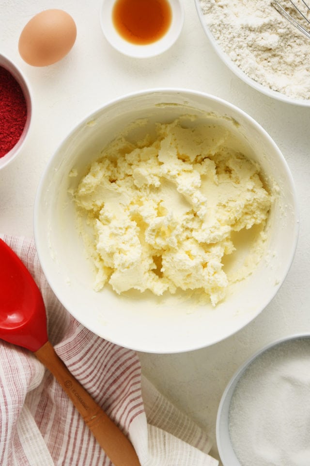 Overhead view of butter and cream cheese mixed in a white mixing bowl.