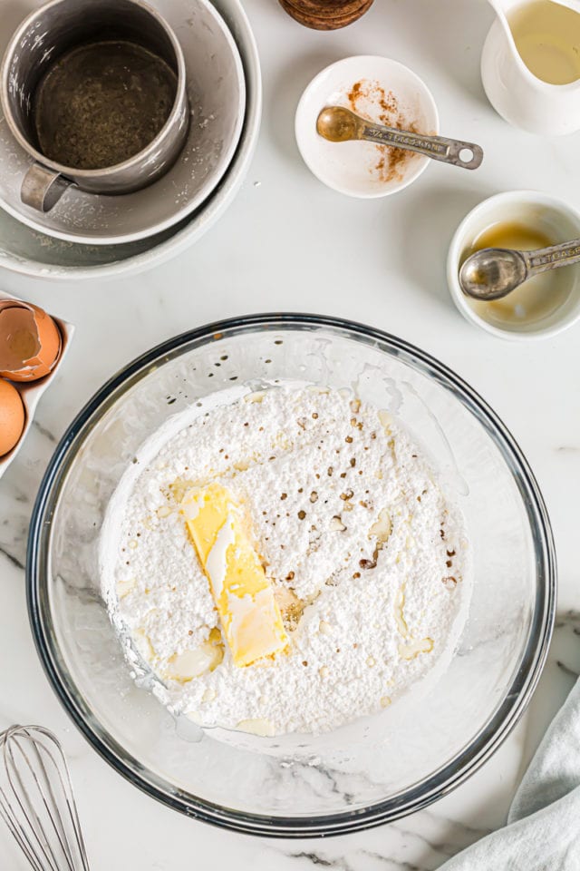 Overhead view of buttercream ingredients in glass mixing bowl