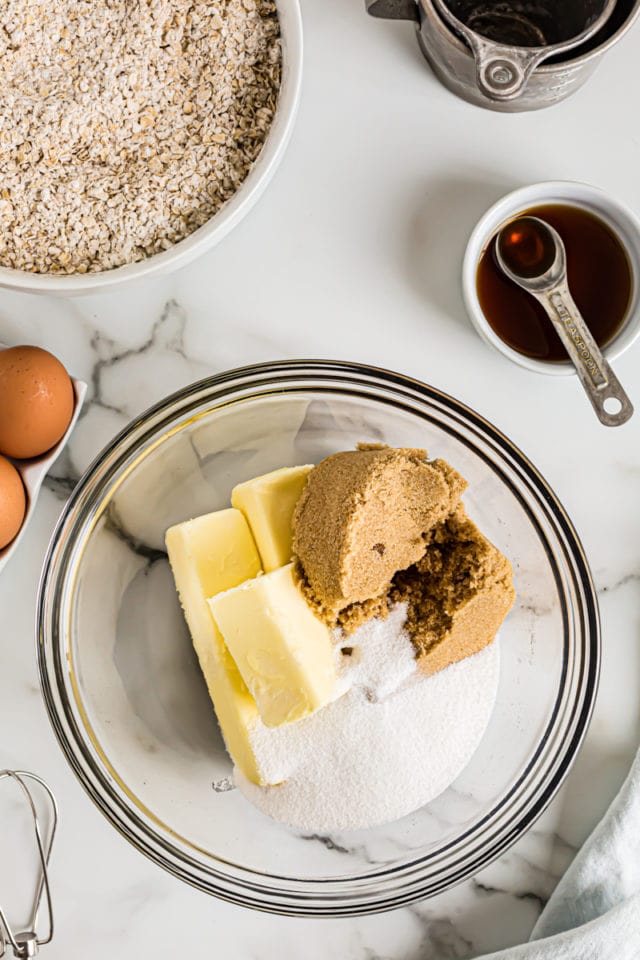 Overhead view of brown sugar, white sugar, and butter in glass mixing bowl