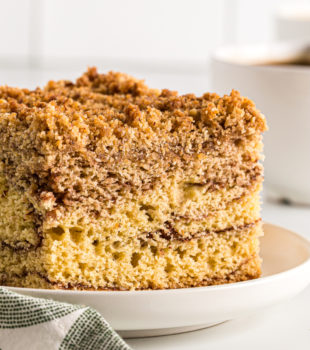 Side view of sour cream coffee cake on a plate, showing layers of cinnamon and chocolate.