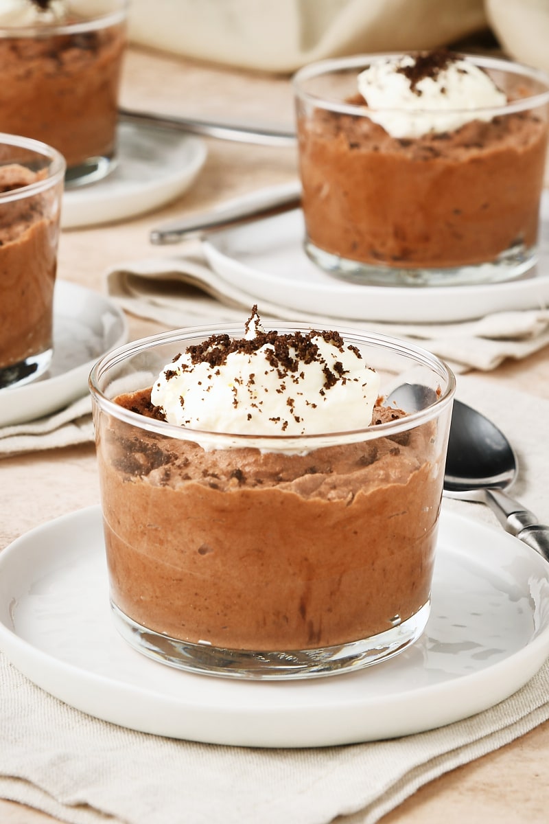 servings of Chocolate Mousse in clear glasses set on small white plates