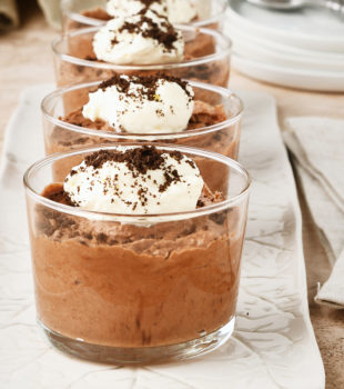 four servings of Chocolate Mousse in clear glasses on a long white tray