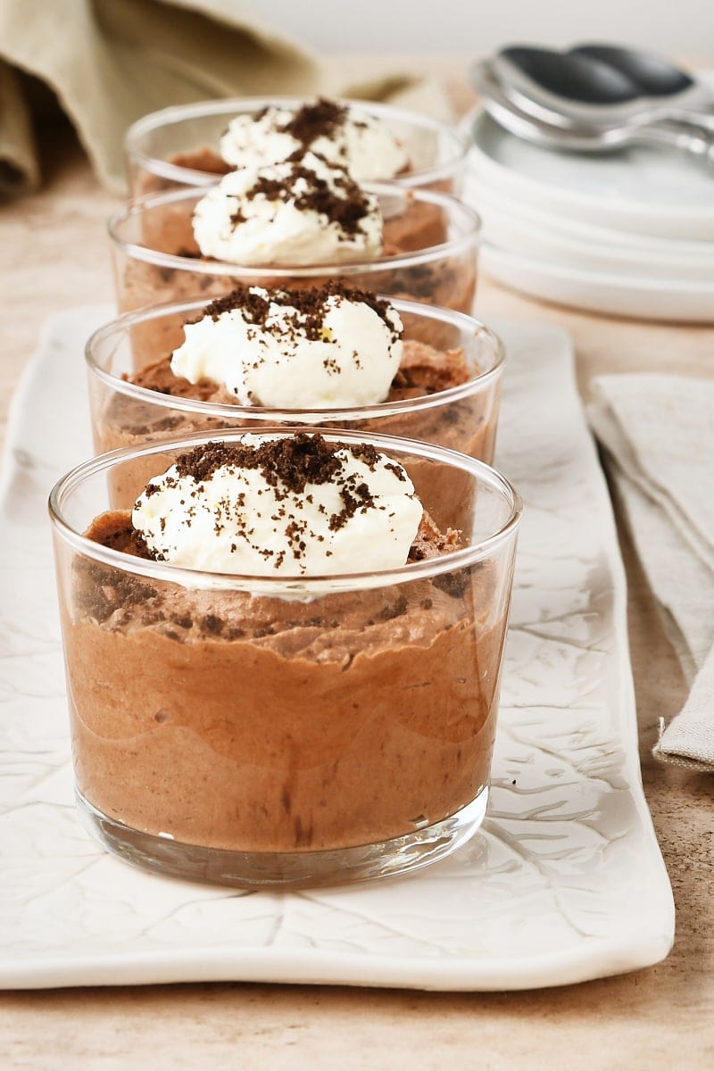 four servings of Chocolate Mousse in clear glasses on a long white tray