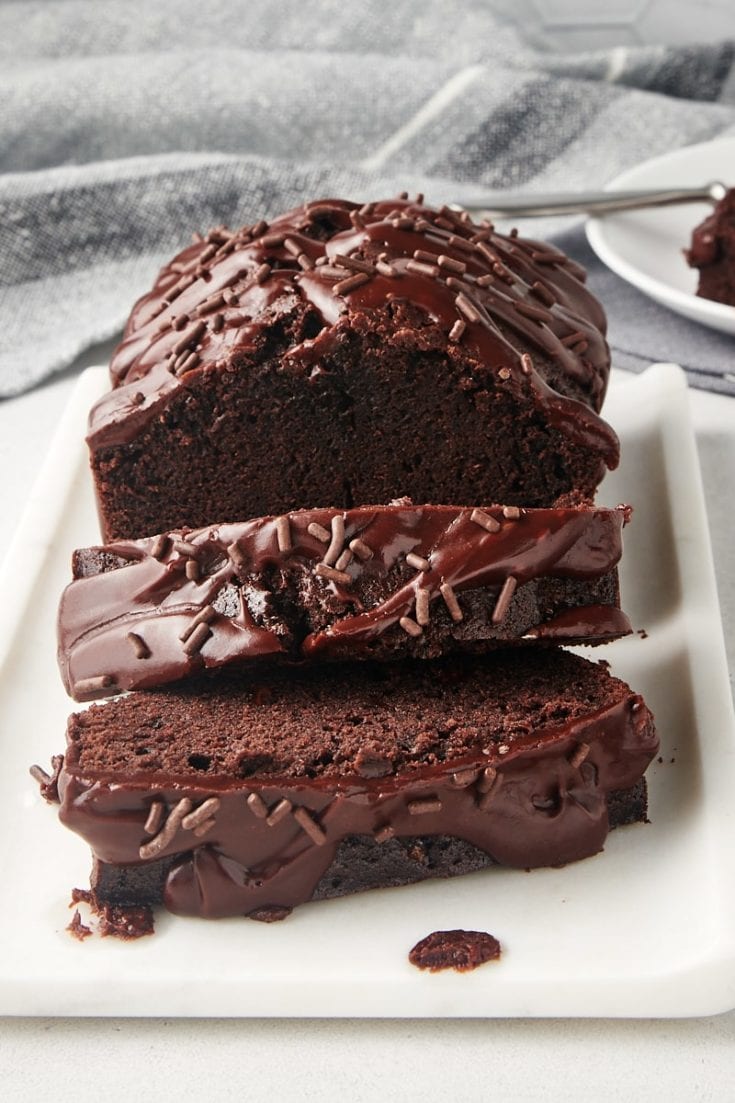 partially sliced Chocolate Loaf Cake on a white serving tray
