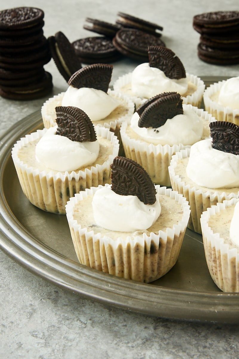 Cookies and Cream Cheesecakes on a pewter tray with stacks of Oreos in the background
