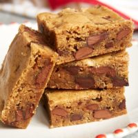 stack of Double Chocolate Chunk Blondies on a red-trimmed white plate