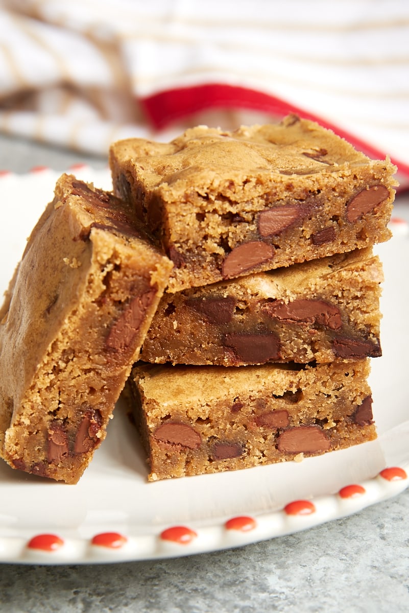 stack of Double Chocolate Chunk Blondies on a red-trimmed white plate