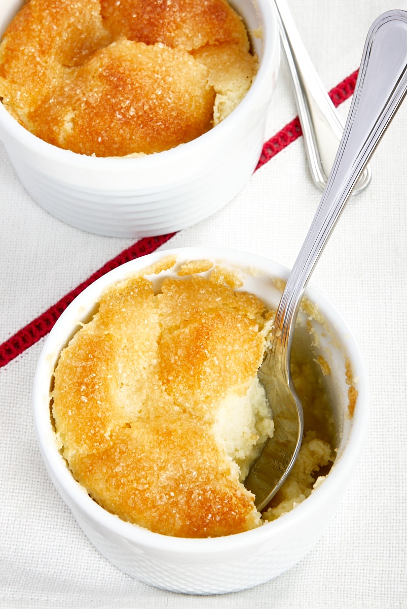 two Meyer Lemon Pudding Cakes in white ramekins with a spoon sticking out of one of them