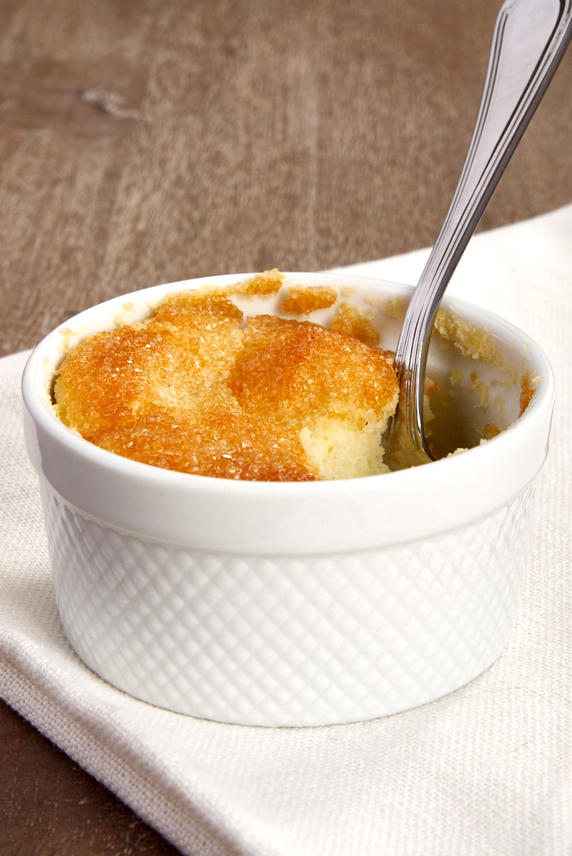 a Meyer Lemon Pudding Cake in a white ramekin with a spoon sticking out of it