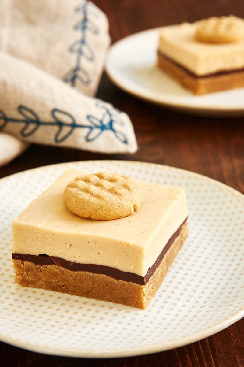 sliced Peanut Butter Cheesecake Bars on white and beige plates