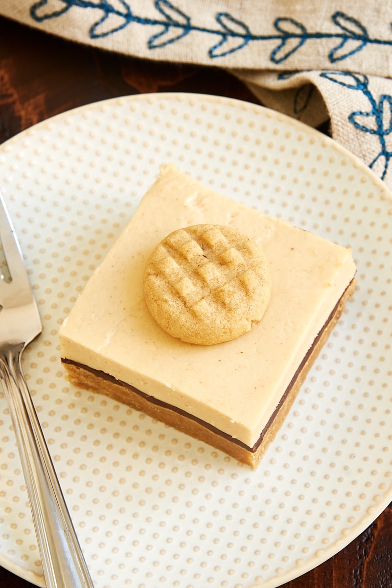 a Peanut Butter Cheesecake Bar on a white and beige plate