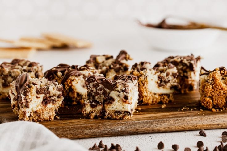 Chocolate chip cookie dough cheesecake bars on wooden cutting board