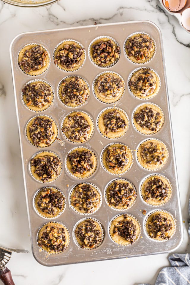 Overhead view of chocolate chip cupcakes in muffin tin after adding topping