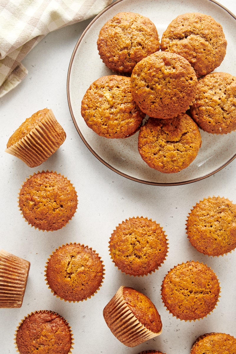 overhead view of Banana Nut Muffins on a plate and scattered on a white surface