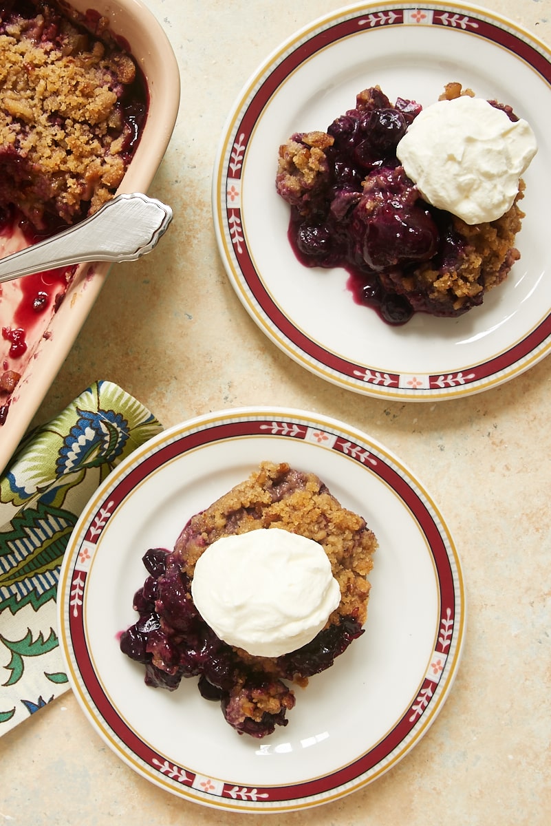 Two servings of Cherry Berry Crumble on plates topped with sweetened whipped cream