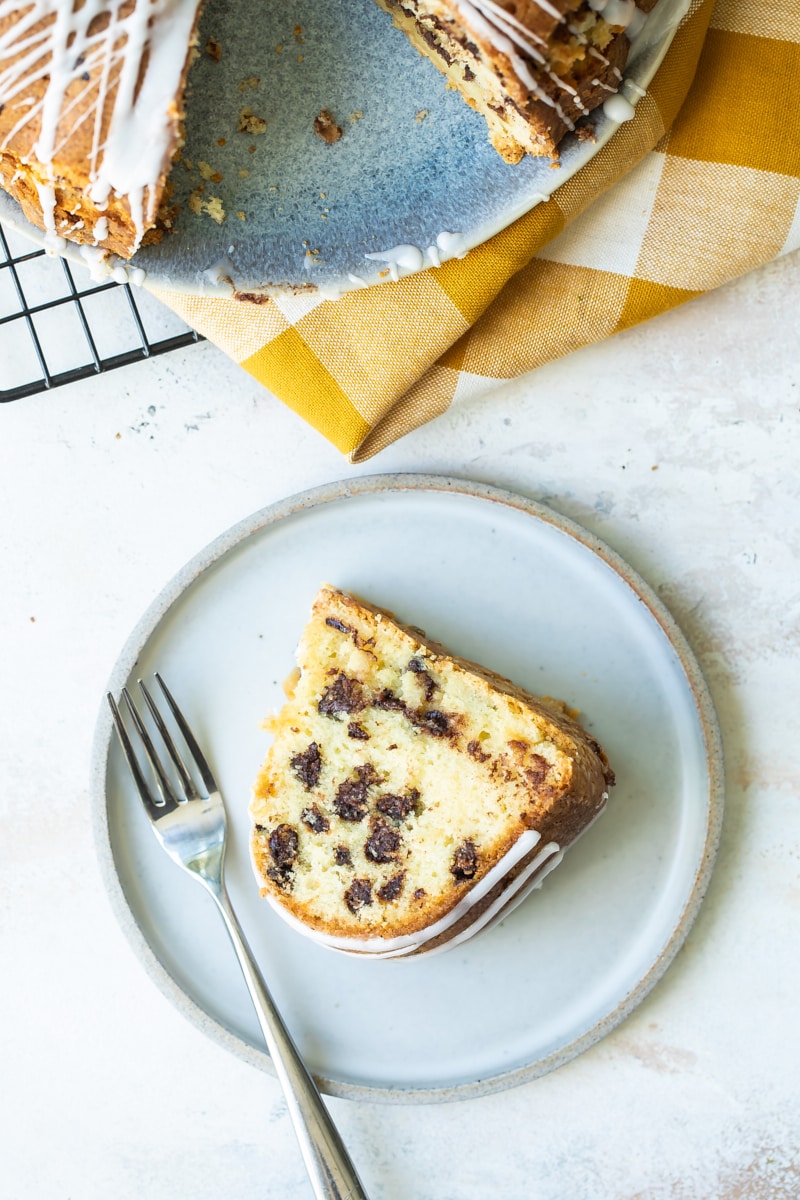 overhead view of a slice of Chocolate Chip Almond Cake on a gray plate and the remaining cake on a cake plate