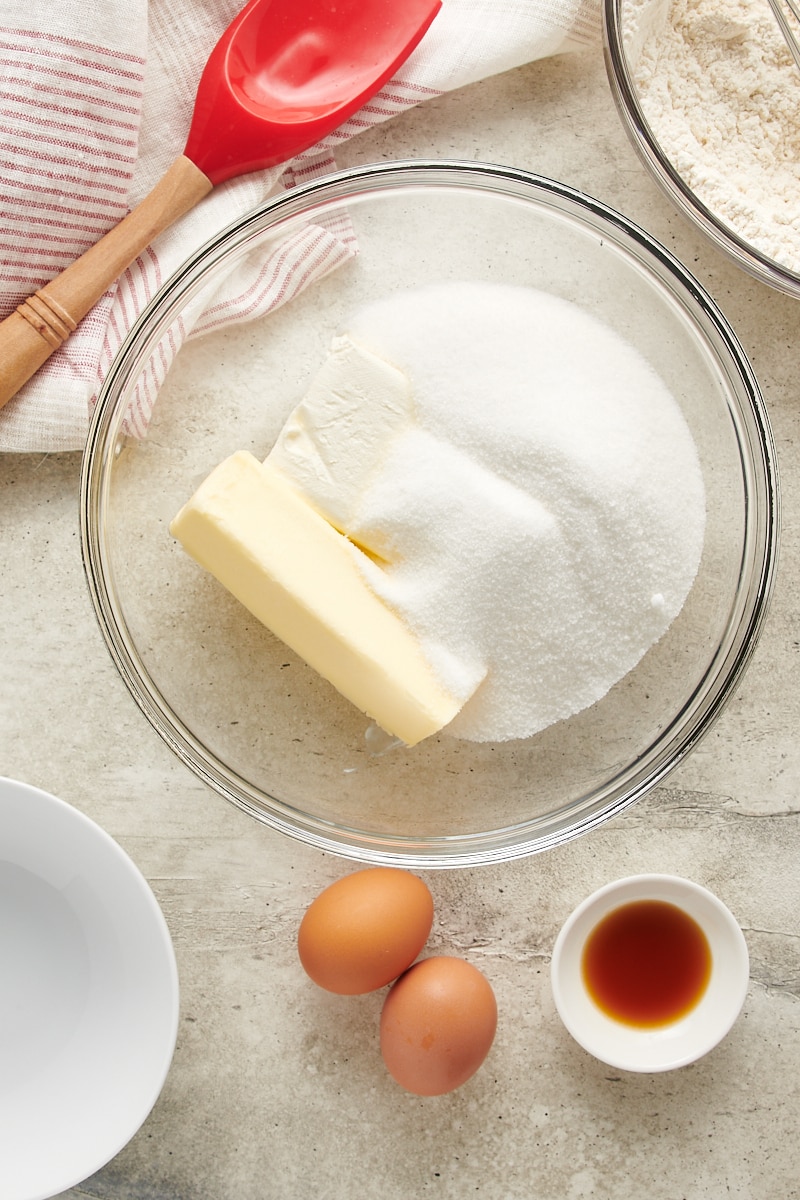 overhead view of butter, cream cheese, and sugar in a glass mixing bowl