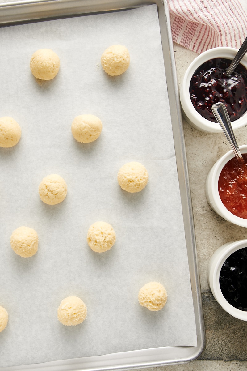 balls of Cream Cheese Thumbprint Cookie dough on a parchment-lined baking sheet